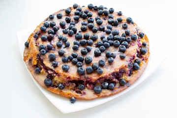 A large homemade pie with black currants (not all berries are specially focused) in natural light, on a white plate