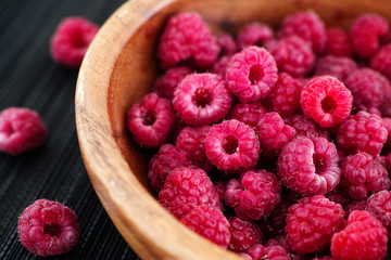 Ripe raspberries in a wooden bowl