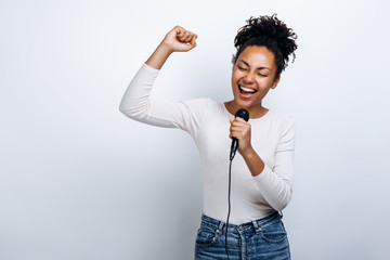 Cute girl sings into a microphone, has fun singing on a white background