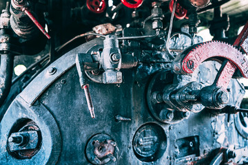 Huge vintage steam locomotive interior, black and red painted steel train. Coal-powered steam express on tracks. Classic gigantic heavy railway machinery. Inside view of power parts of machine.