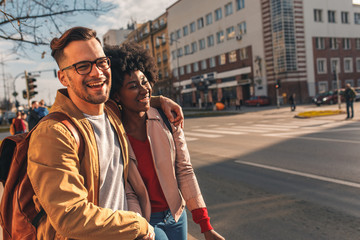 Smiling mix couple enjoying on vacation, young tourist having fun walking and exploring city street during the day.	