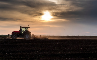 Tractor is preparing the land at dusk