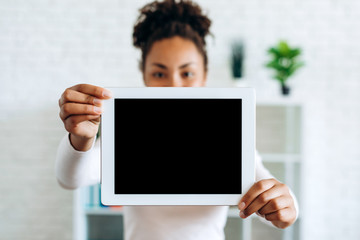 Girl holding a tablet with a blank screen on a blurred background