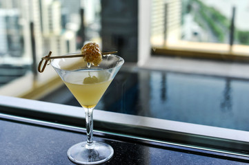 A signature yellow cocktail in martini glass decorated with fresh honeycomb