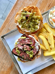 Pastrami Burger with Mustard and Pickles served with Potatoes.