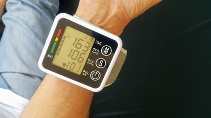 Measure your blood pressure at home using a portable device to check Your health. The device shows a high pressure value.