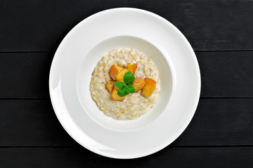 Oatmeal porridge with baked apple in white bowl