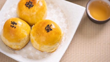 Tasty baked egg yolk pastry moon cake for Mid-Autumn Festival on bright wooden table background. Chinese festive food concept, close up, copy space.
