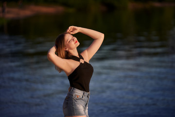 woman in black tank top and denim shorts on the beach. teenager girl on the lake.