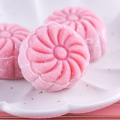 Colorful snow skin moon cake, sweet snowy mooncake, traditional savory dessert for Mid-Autumn Festival on pastel pale pink background, close up, lifestyle.