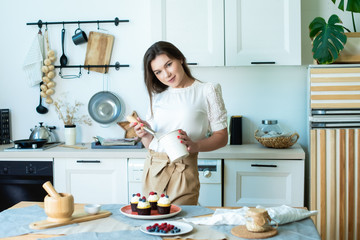 pretty housewife smiles and prepares muffins with colored berries. garnishes with raspberries and blueberries. Lifestyle