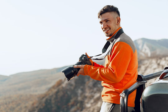 Young man traveler taking photos of mountains with professional camera