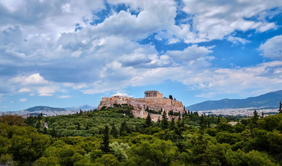 Fototapeta na wymiar View of Acropolis hill and theater of Odeon in Athens, Greece from the hill of Philoppapos or Muses in summer daylight with great clouds in blue sky.