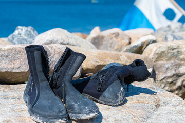Dive boots drying on a boulder. A dive flag and blue water in the background