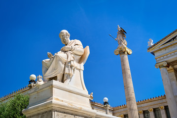 Statue of Plato, great ancient Greek philosopher, seated in chair and column with statue of Athena, ancient Greek goddess. Academy of Athens, Greece.