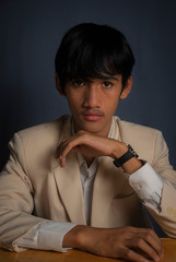 Fototapeta na wymiar Young male model wearing khaki blazer/suit with white shirt over dark grey background