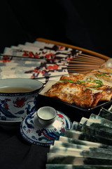Vertical material of traditional chinese fried dumplings(also called gyoza,pot sticker) on table with black background and decorate with chinese style fans and tea cup.