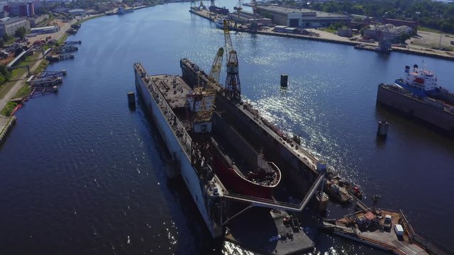 Aerial view of the ship in floating dry dock under repair by sandblasting in Riga, Latvia.