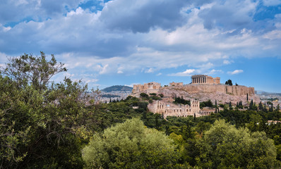 Fototapeta na wymiar View of Acropolis hill and theater of Odeon in Athens, Greece from the hill of Philoppapos or Muses in summer daylight with great clouds in blue sky.