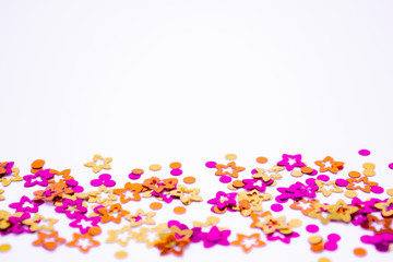Scattered round confetti and in the form of flowers pink, gold and orange color on a white background. Copy space. Spring and summertime, birthday and wedding concept