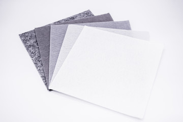 Five square pieces of felt of different shades of gray from dark to very light, isolated. Grey spectrum. Copy space