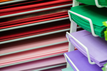 Stacks of colored paper in red, pink, lilac, and green