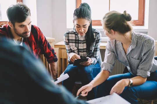 Young concentrated professionals collaborating on design planning and searching useful information on webpages for improving architectural sketch on digital touch pad connecting to 4G internet