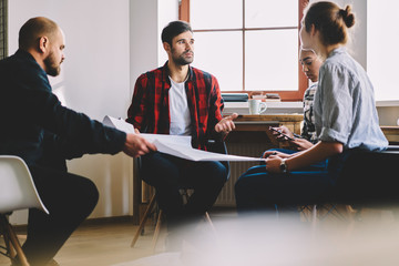 Crew of professional male and female architects brainstorming together making concept planning for startup project searching useful information on internet via touchpad using 4G wireless connection