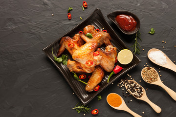 Rosemary baked chicken served on a black plate with lemon sauce tomato garlic and spices placed on a black table Top view and there is a blank space for designing the text.