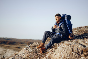 Young male hiker sitting and having a rest on a halt stop