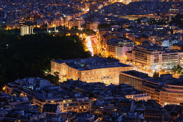 Fototapeta na wymiar Night view Hellenic Parliament in Syntagma square brightly lit up and ruins of temple of Olympian Zeus behind it shot from hill of Lycabettus,