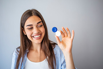 Woman holding plastic container with contact lenses, indoors. Young woman holds case for contact lenses.  Woman holding contact eye lenses container