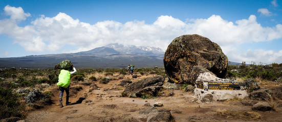 guides porters and sherpas carry heavy sacks as they ascend mount kilimanjaro the tallest peak in...