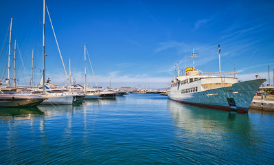Fototapeta premium Boats and yachts anchored or moored in Athens marina and by its promenade in Glyfada on a bright summer day. Athens, Greece