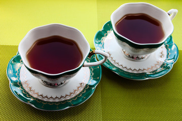 Two cups of tea on a bright green background.