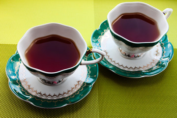 Two cups of tea on a bright green background.