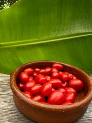 Tomatoes in Bowl on wooden table with banana leaf