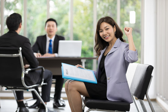 asian woman holding her resume and raised hand for success applying a job