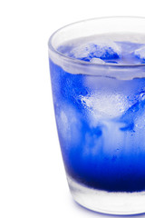 Glass refreshing beverage with melting ice cubes in blue syrop and condensation on its wall isolated white background macro