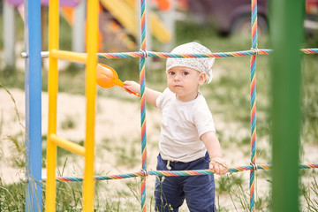Obraz premium A cute child in a bandana is holding on to the stairs in the playground.