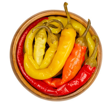 Peperoni Pickles In A Wooden Bowl. Pickled Whole Chili Peppers Of Different Bright Colors. Vegetable, Preserved In Brine. Capsicum. Close-up From Above, On White Background, Isolated Macro Food Photo.