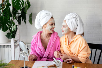 Mother and her daughter put natural musk on face for better skin and towels on head