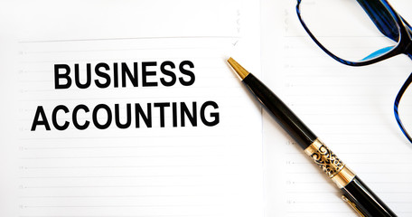 In the notebook the inscription - BUSINESS ACCOUNTING, next to a pen. Finance and business concept.
