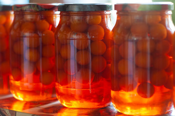 Three large cans, canned plums - compote. Yellow, orange, red. Soft focus.
