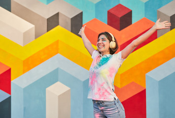Happy young woman listening to music during paint festival