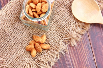 top view roasted organic brown almond seed  on sack floor  and  some of almond in the  square bottle,copy space.