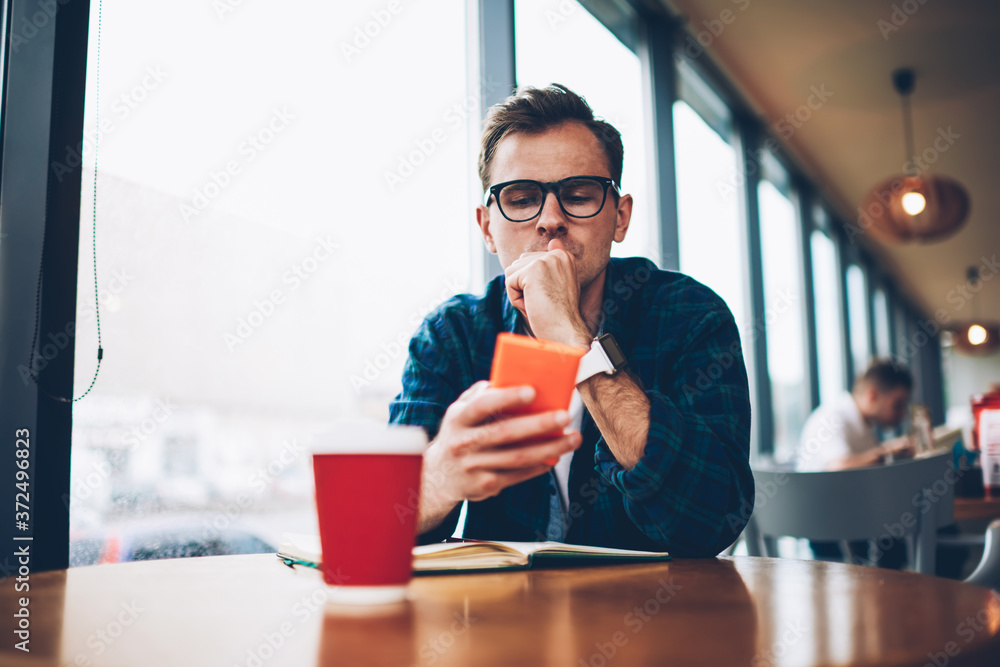 Poster handsome pensive smart male student dressed in trendy outfit texting email message using application