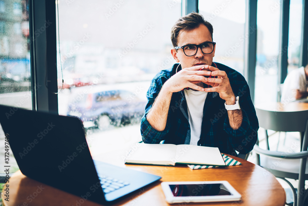 Poster handsome contemplative professional it developer in trendy eyeglasses pondering about task for imple
