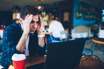Good looking intelligent student dressed in casual clothing deeply thinking while preparing for upcoming examinations in cafe.Smart professional developer feeling tired during remote work indoors