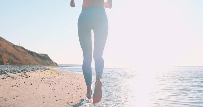 young athletic woman jogging along the seashore